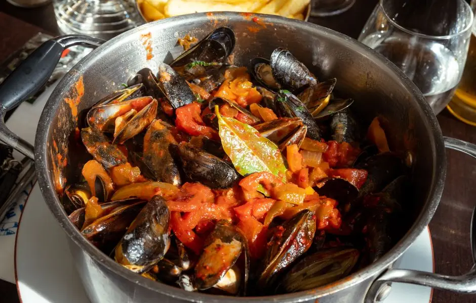 Moules marinière ouvertes dans une casserole, persil et vin blanc, vue gourmande